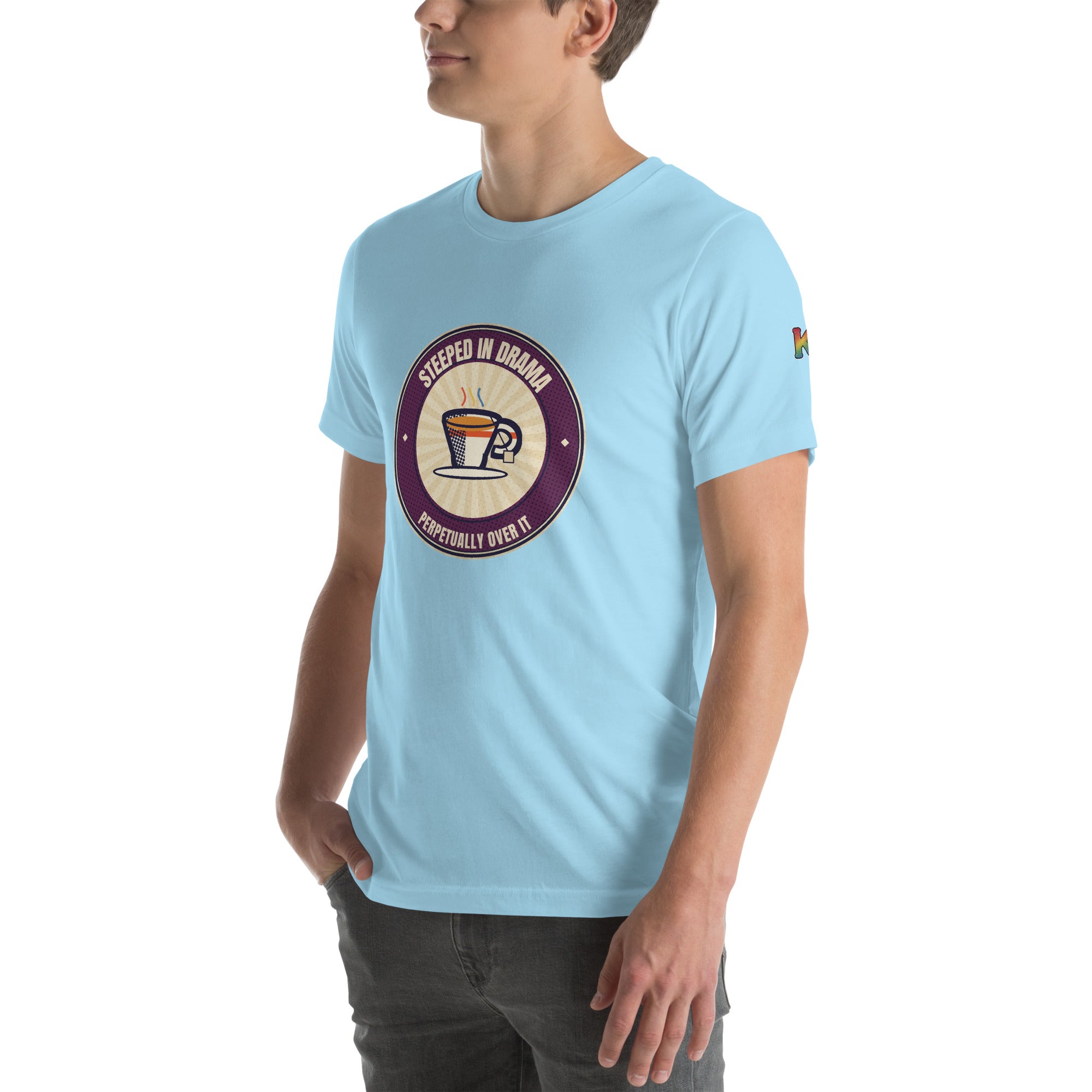 LGBTQ+ pride t-shirt — Steeped in Drama badge design, ocean blue tee left-front angled view (sleeve K visible)